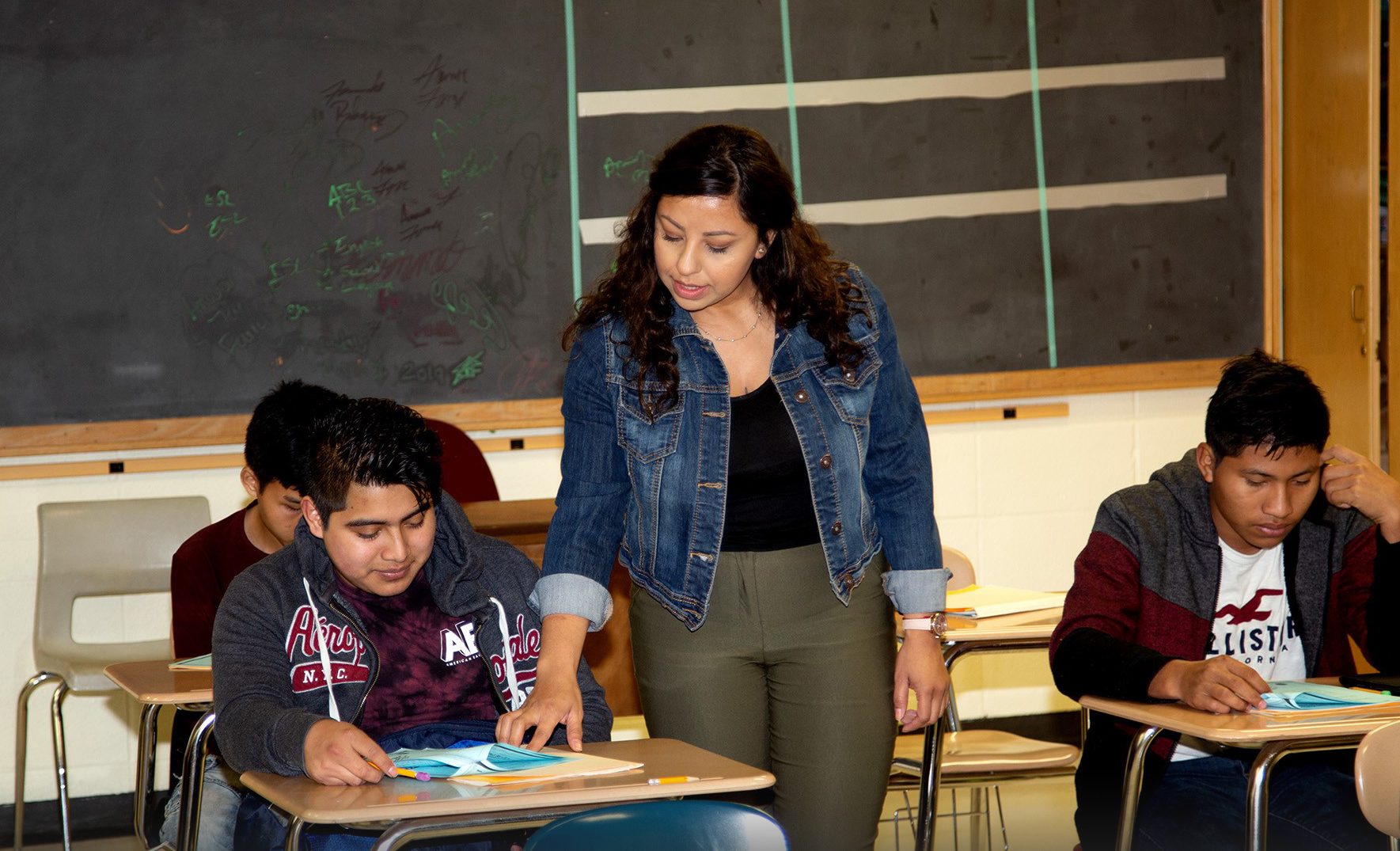 High school teacher instructs a student in a classroom.
