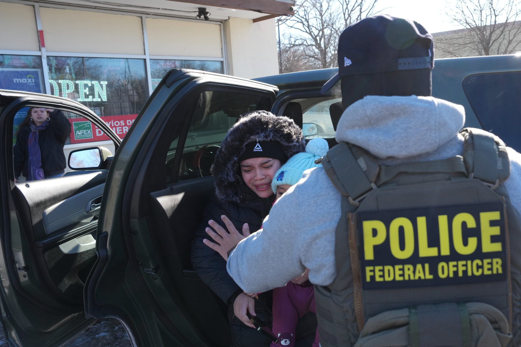 A woman and child are detained while an observer films outside a local business. Photo credit: Adam Gray, Associated Press