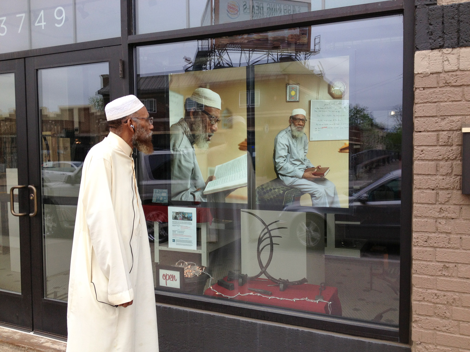 A man looks at photos of himself displayed in the window of a business for a public art display