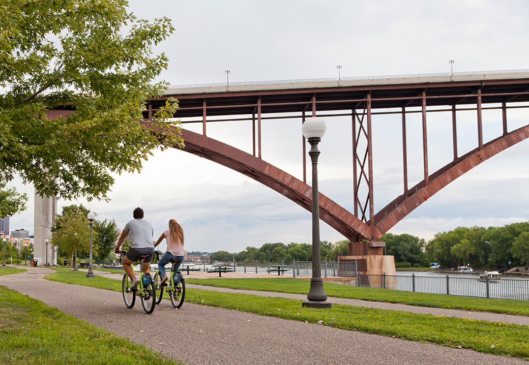 A couple riding bicycles along Mississippi River in St. Paul, MN. Photo credit: Bogdan Denysyuk/Shutterstock.com