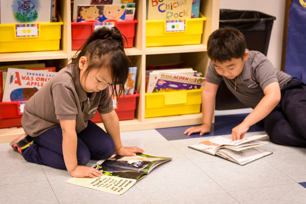 two elementay kids sitting and reading a book