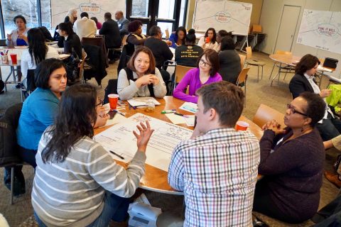 A group of people sitting around a round table having a discussion.