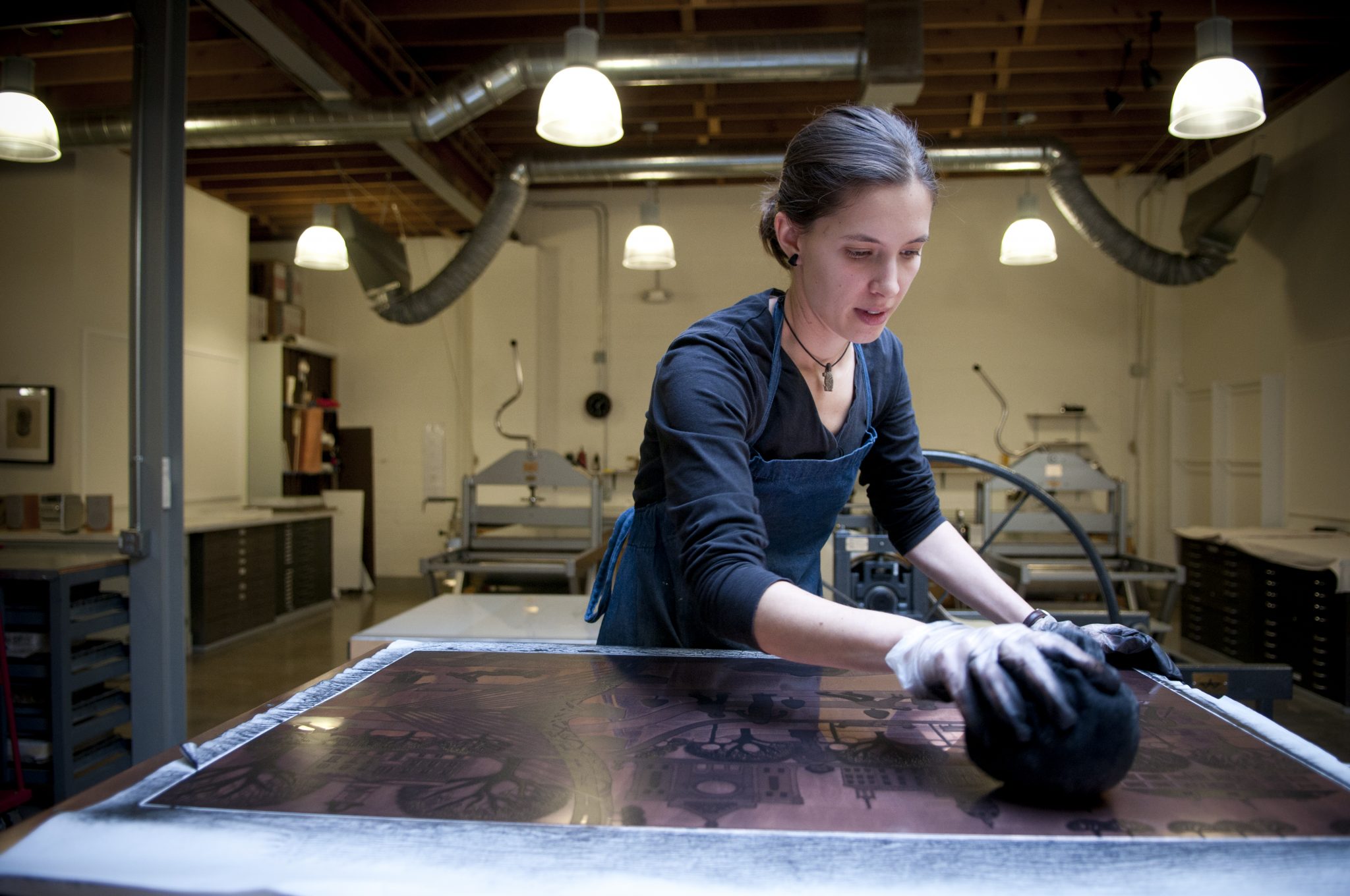 HPCoopArtist Co-op artist Miriam Rudolf wipes ink on an etching plate, preparing it so she can print on the press.