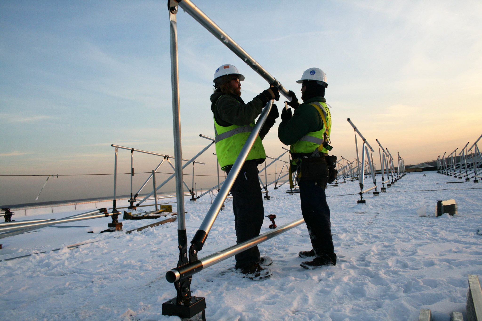 2 people in hard hats assemble a solar panel