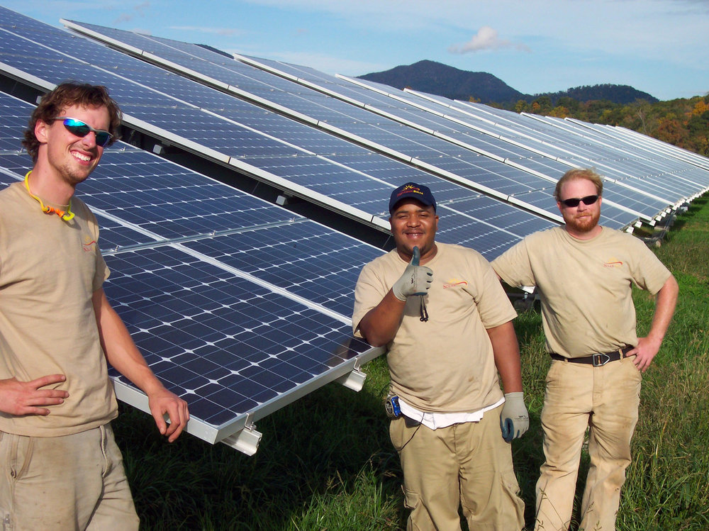 three men standing infront of solar panels