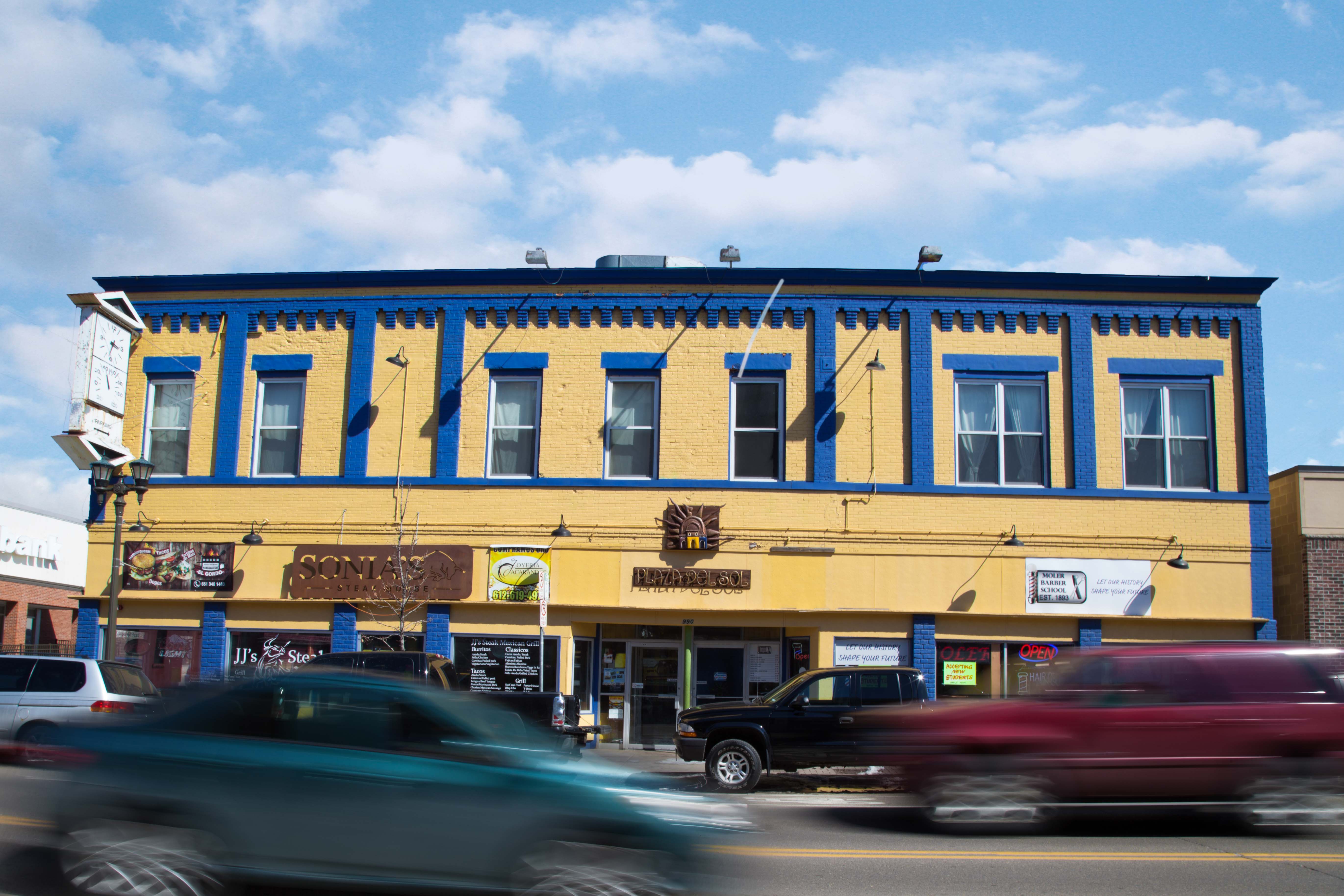 The outside of Plaza Del Sol, a bright yellow building with blue trim.