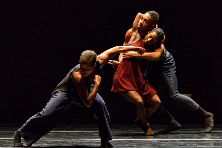 Three people dance dramatically on stage.