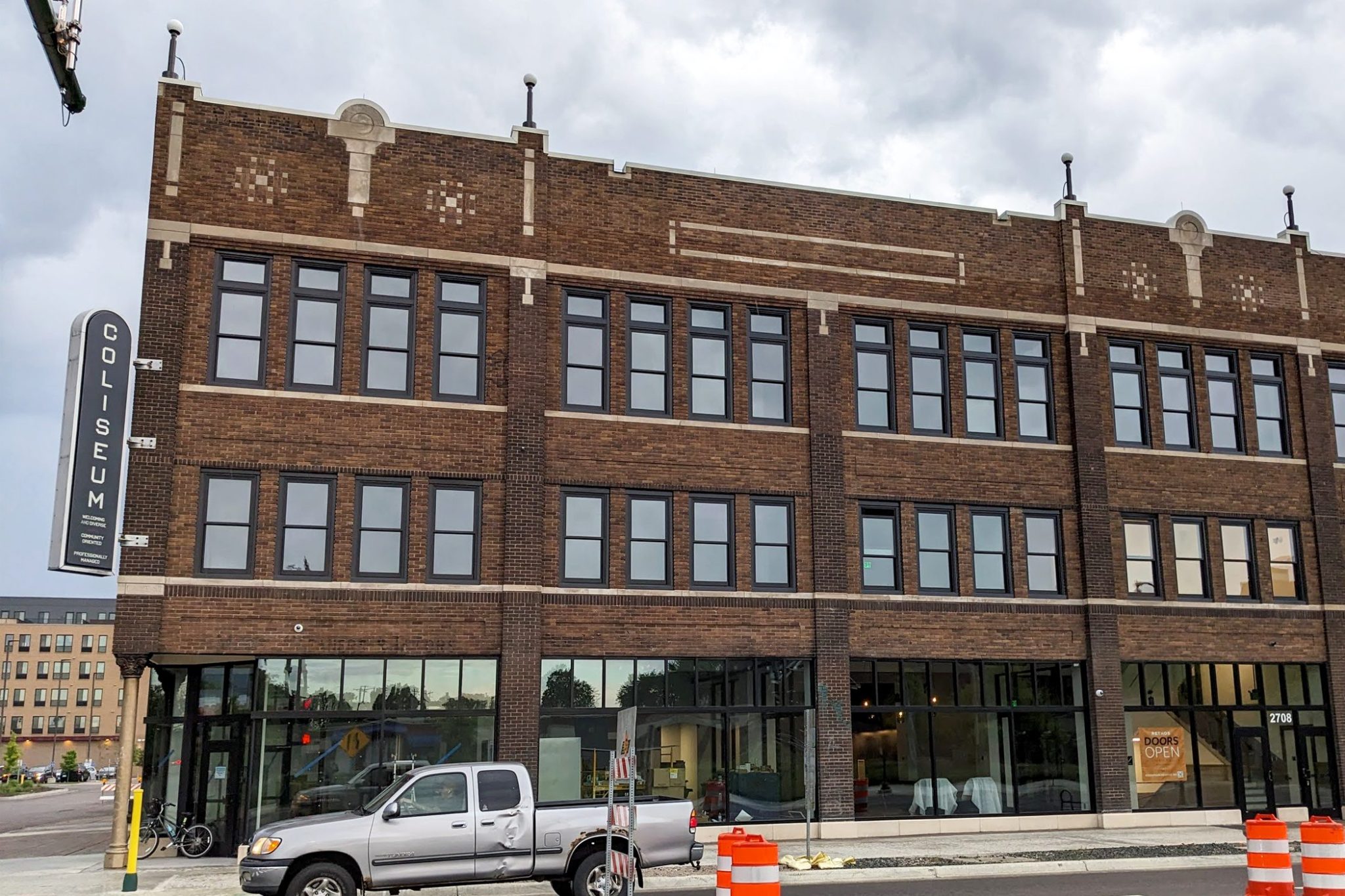 A large three story brick building with a black marquee sign that says COLISEUM