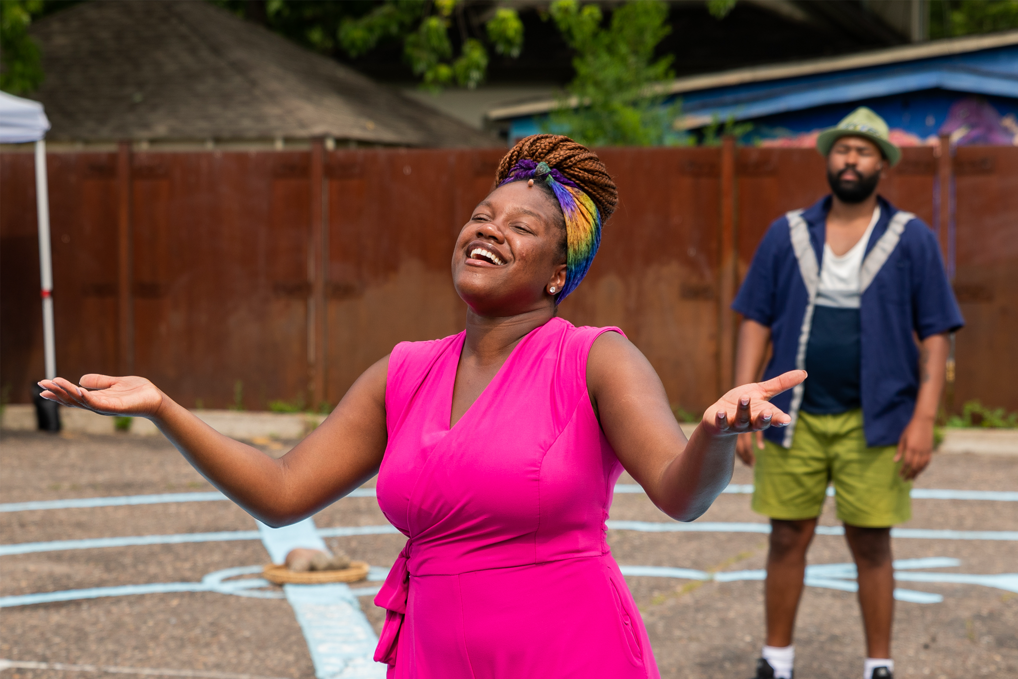 A Black woman smiles with open arms.