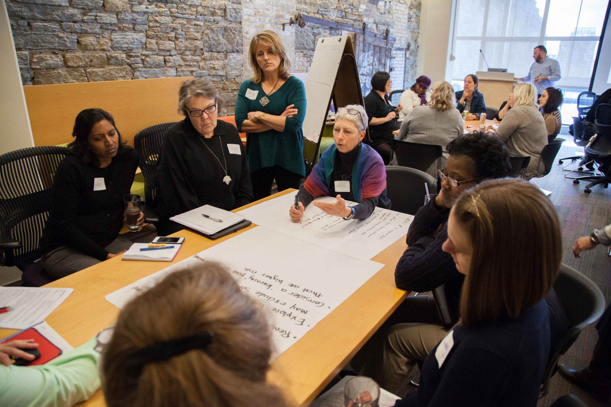 Group of women discuss at table.