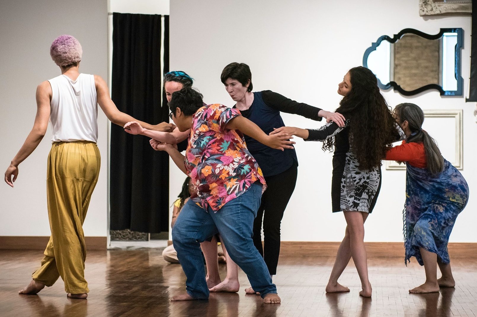 Six people dance in a circle in a dance studio